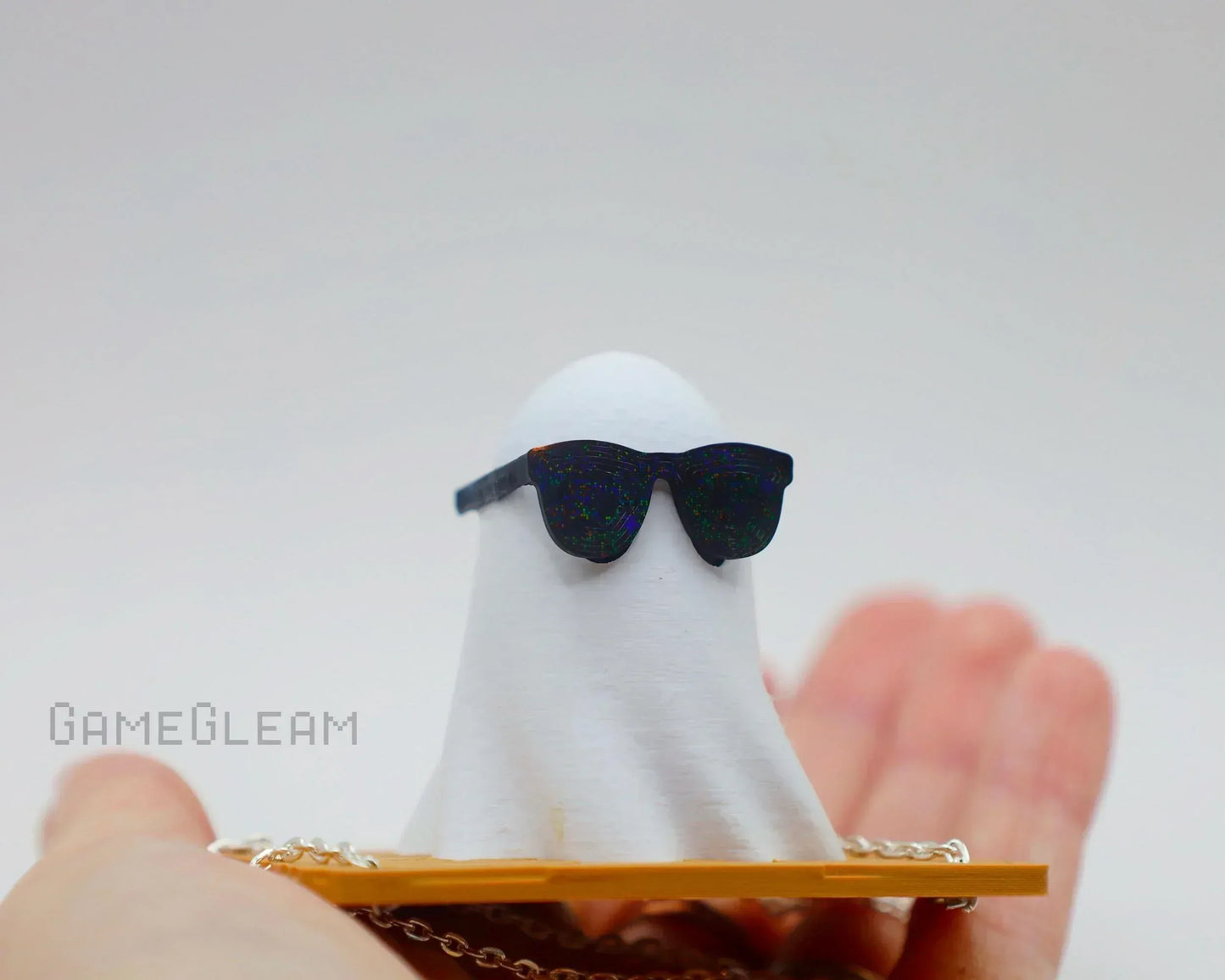 Handmade ghost figurine with sunglasses, unique car charm for gamers, held in hand
