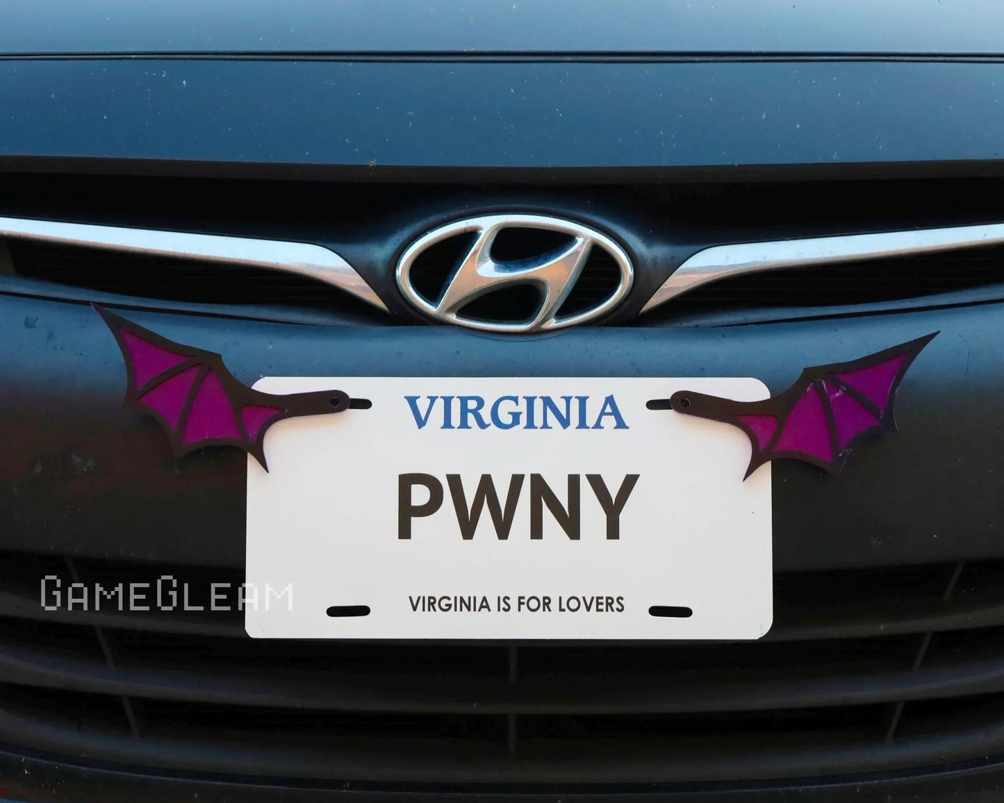 Novelty car license plate frame with purple bat wings mounted on a Hyundai vehicle.