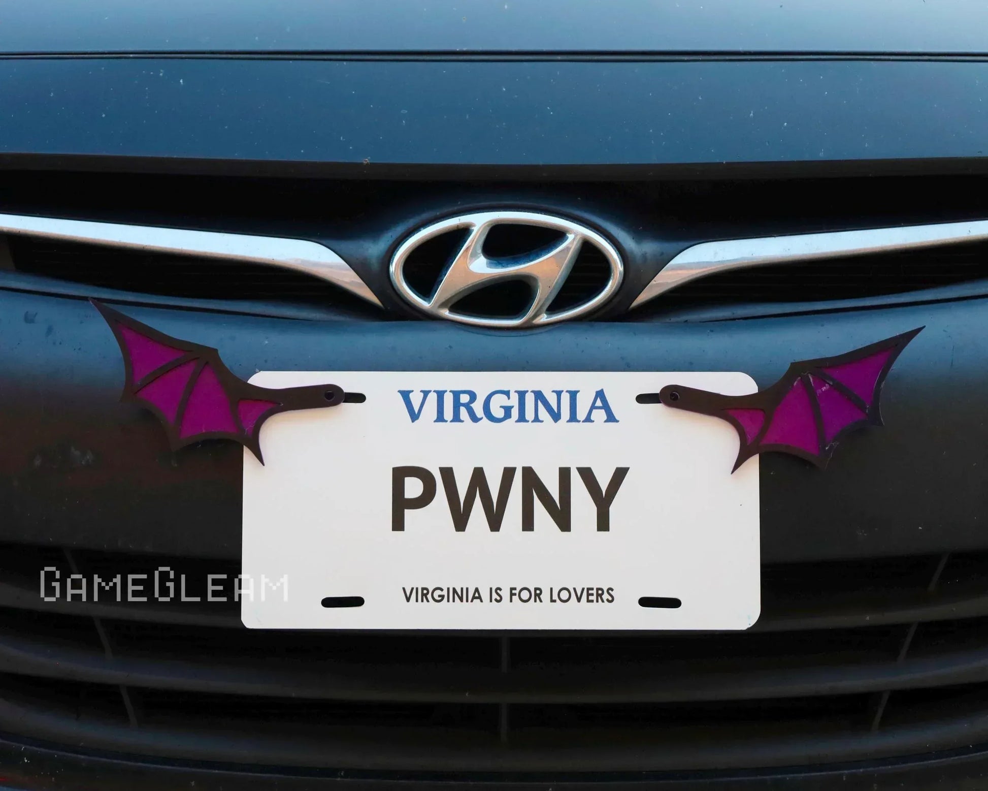 Novelty car license plate frame with purple bat wings mounted on a Hyundai vehicle.