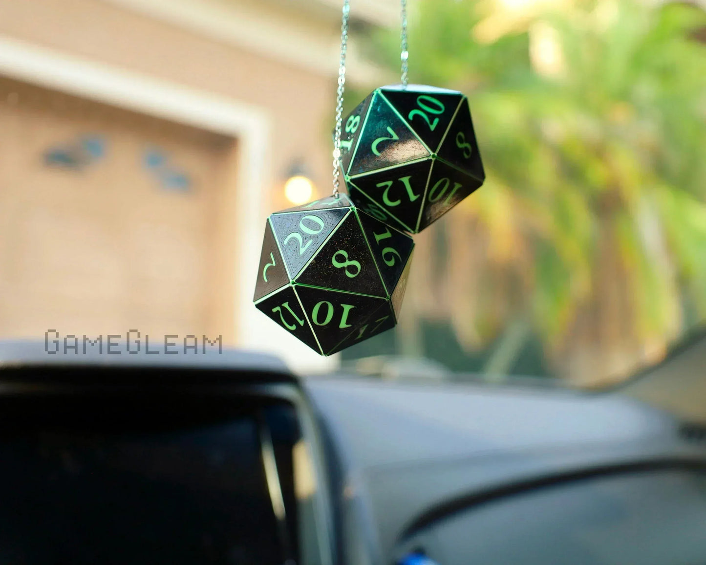 Holographic twenty-sided dice car charm with green numbers hanging from rearview mirror