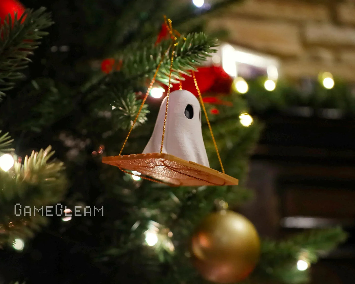 Handmade ghost and dice swing ornament hanging on a Christmas tree with festive lights.