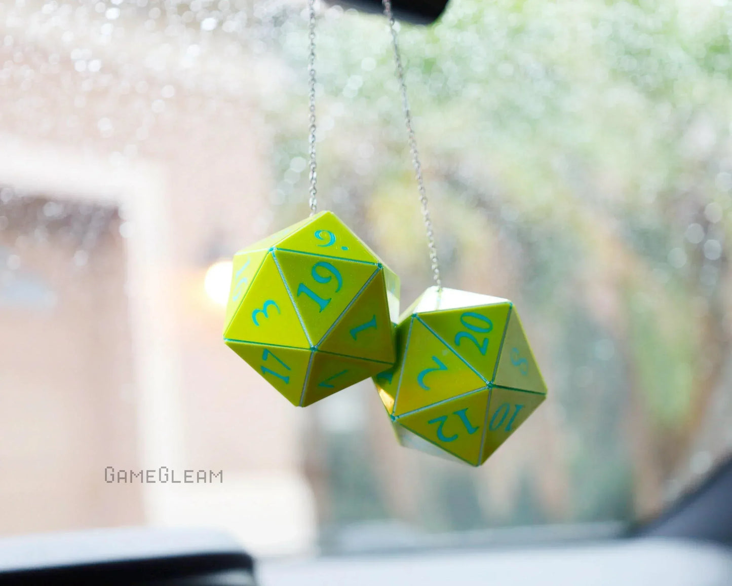 Yellow polyhedral dice car charm with blue numbers hanging from rearview mirror