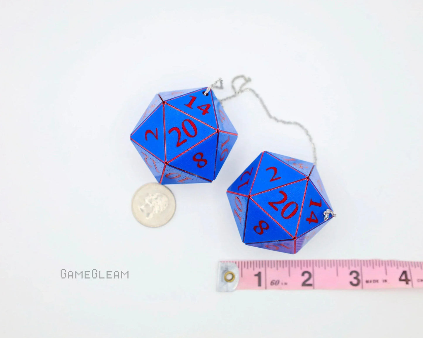 Two blue twenty-sided car dice charms with red numbers, next to a coin and tape measure
