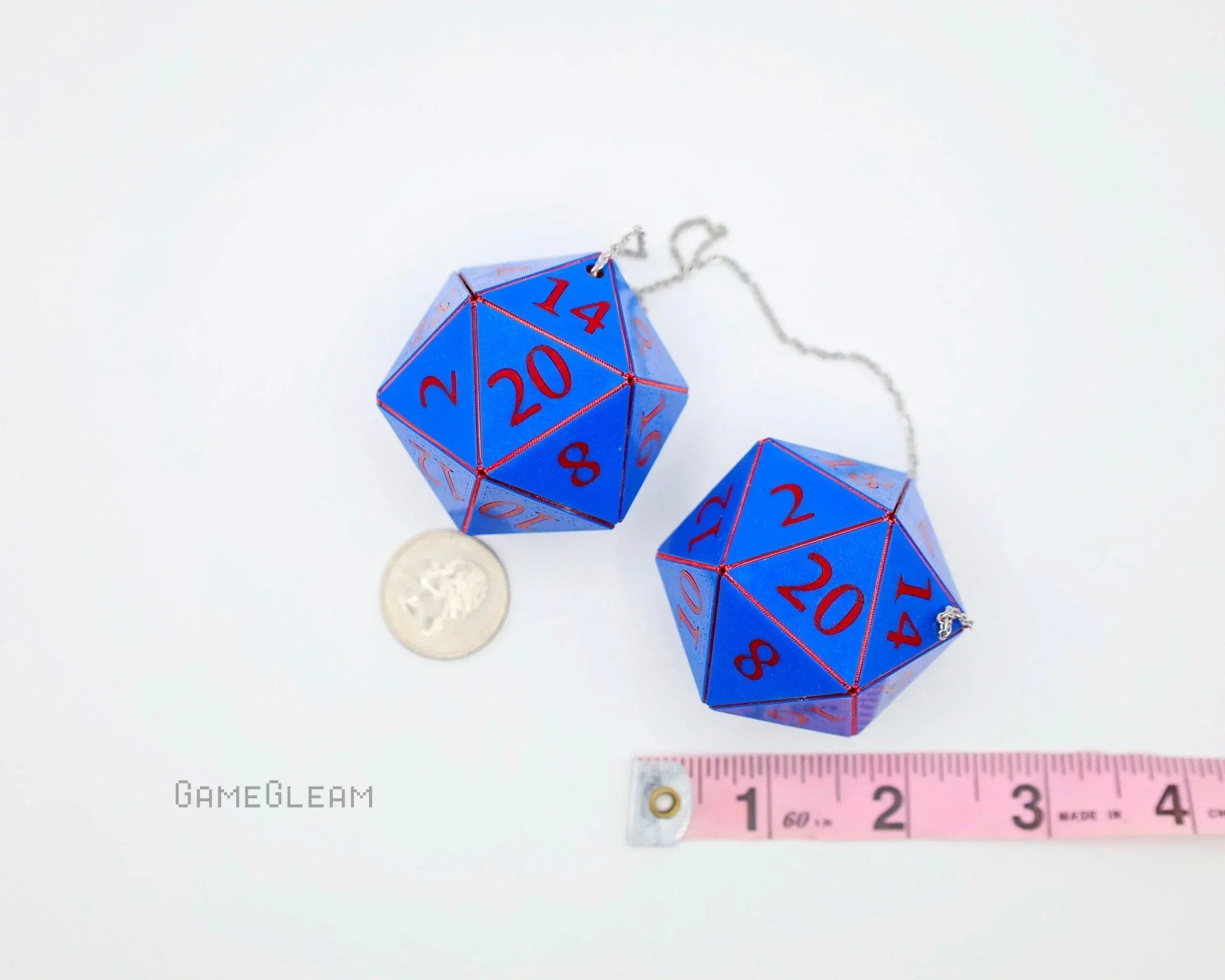 Two blue twenty-sided car dice charms with red numbers, next to a coin and tape measure