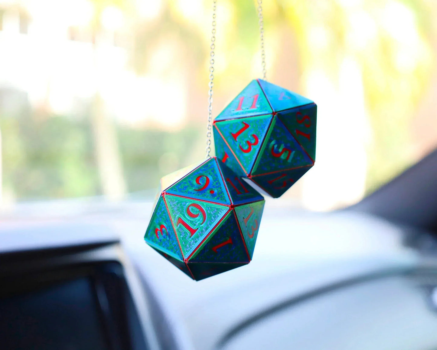 Holographic 20-sided dice car charm with blue and red numbers hanging on a rearview mirror