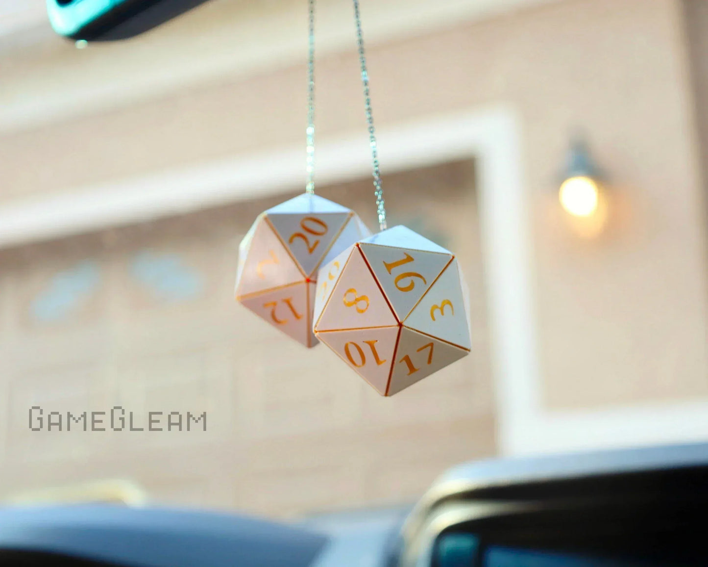 Holographic twenty-sided dice car mirror charm with gold numbers, hanging inside a vehicle