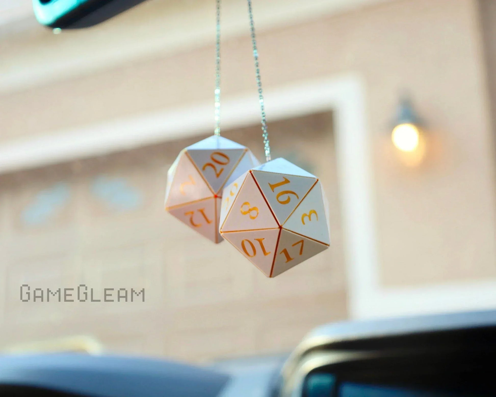 Holographic twenty-sided dice car mirror charm with gold numbers, hanging inside a vehicle