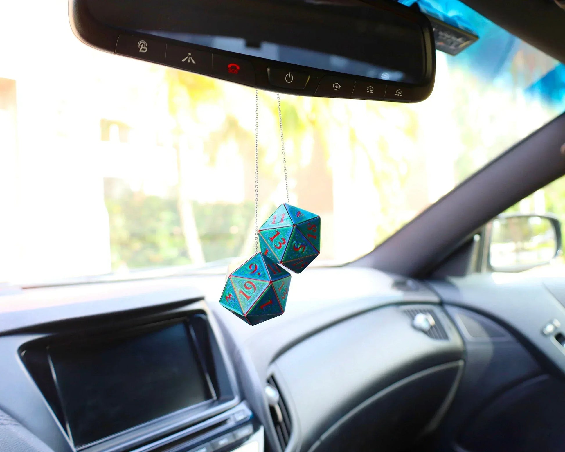 Holographic twenty-sided dice car charm hanging from rearview mirror in a modern vehicle.