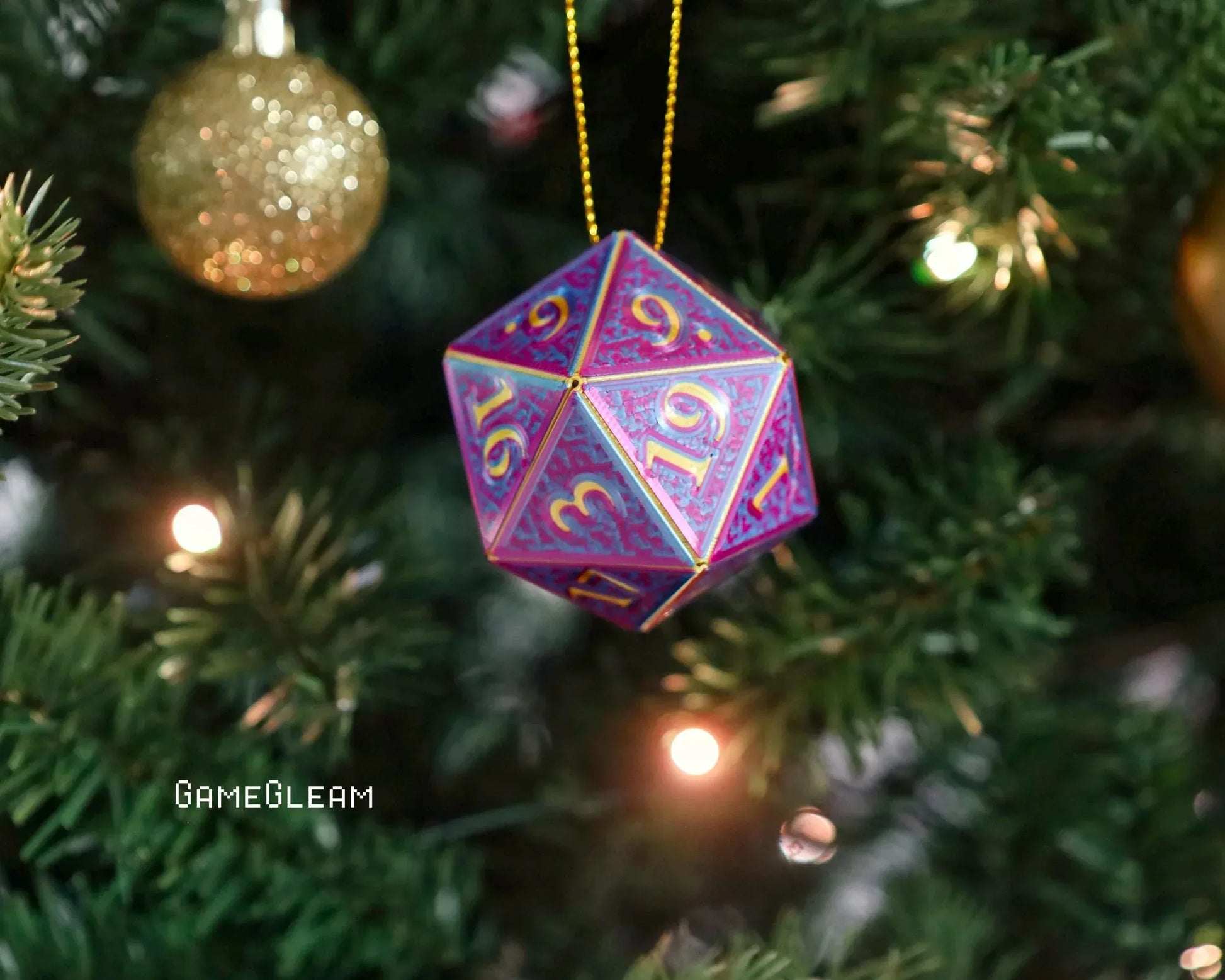 Colorful holographic 20-sided dice ornament hanging on a Christmas tree with gold bauble.