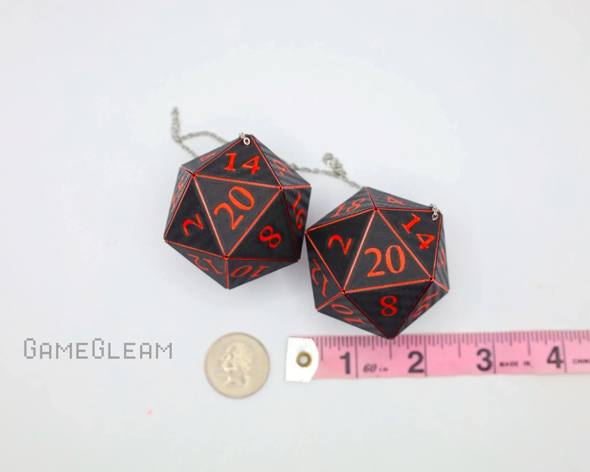 Black and red twenty-sided dice car charm with chain, shown next to a ruler and coin for scale.