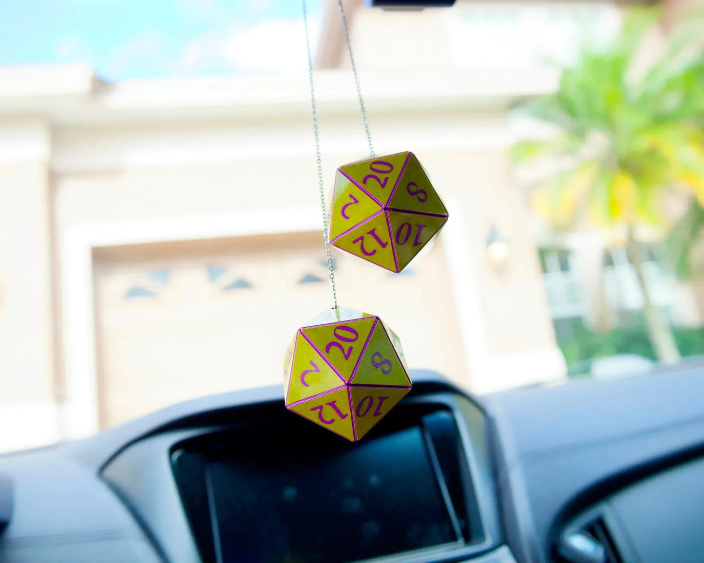 Yellow and purple hanging twenty-sided dice car charm in a vehicle interior