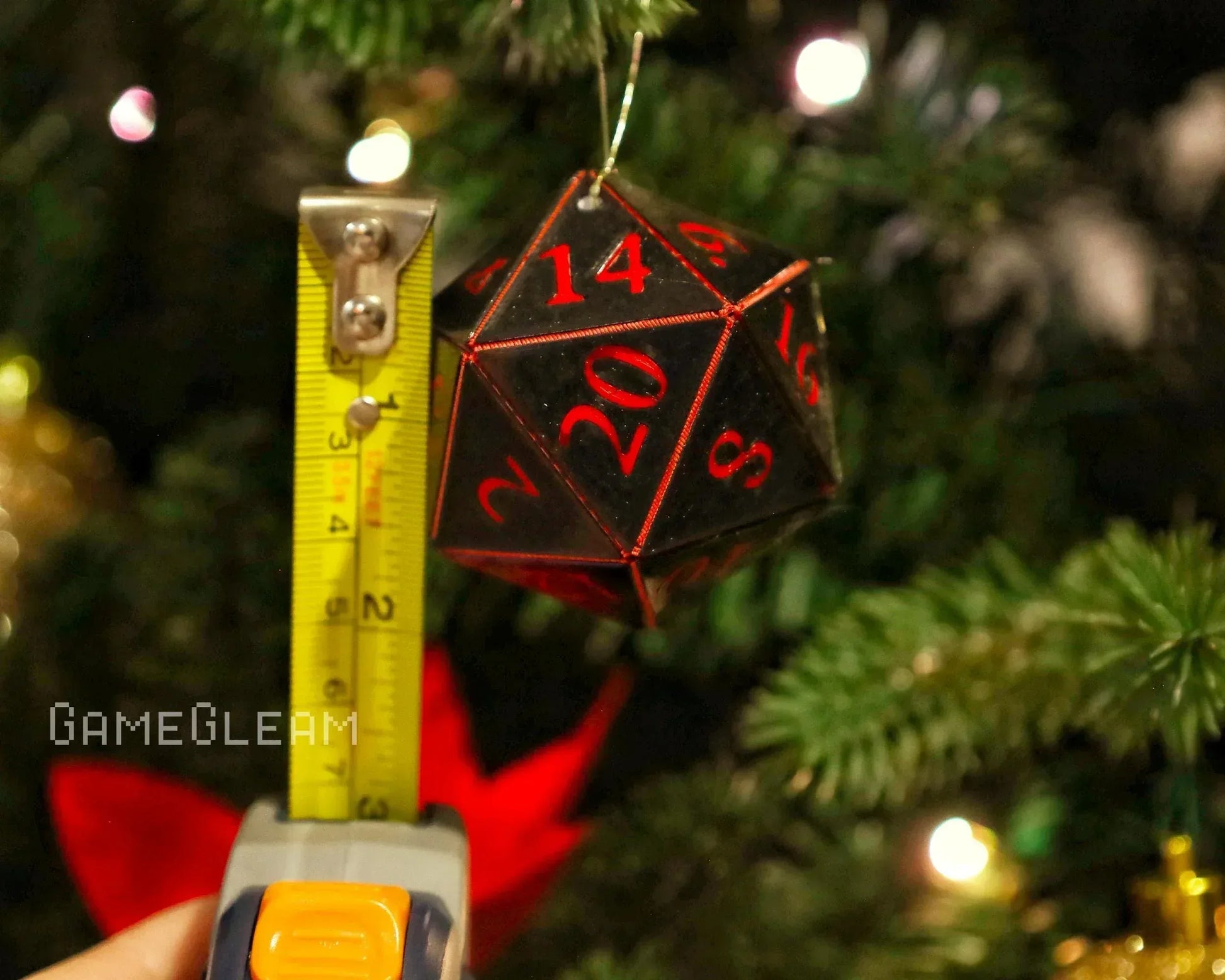 Black and red twenty-sided dice ornament measured with tape, hanging on Christmas tree