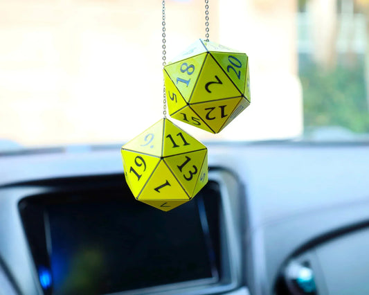 Yellow twenty-sided dice hanging from a car rearview mirror, gamer car accessory.