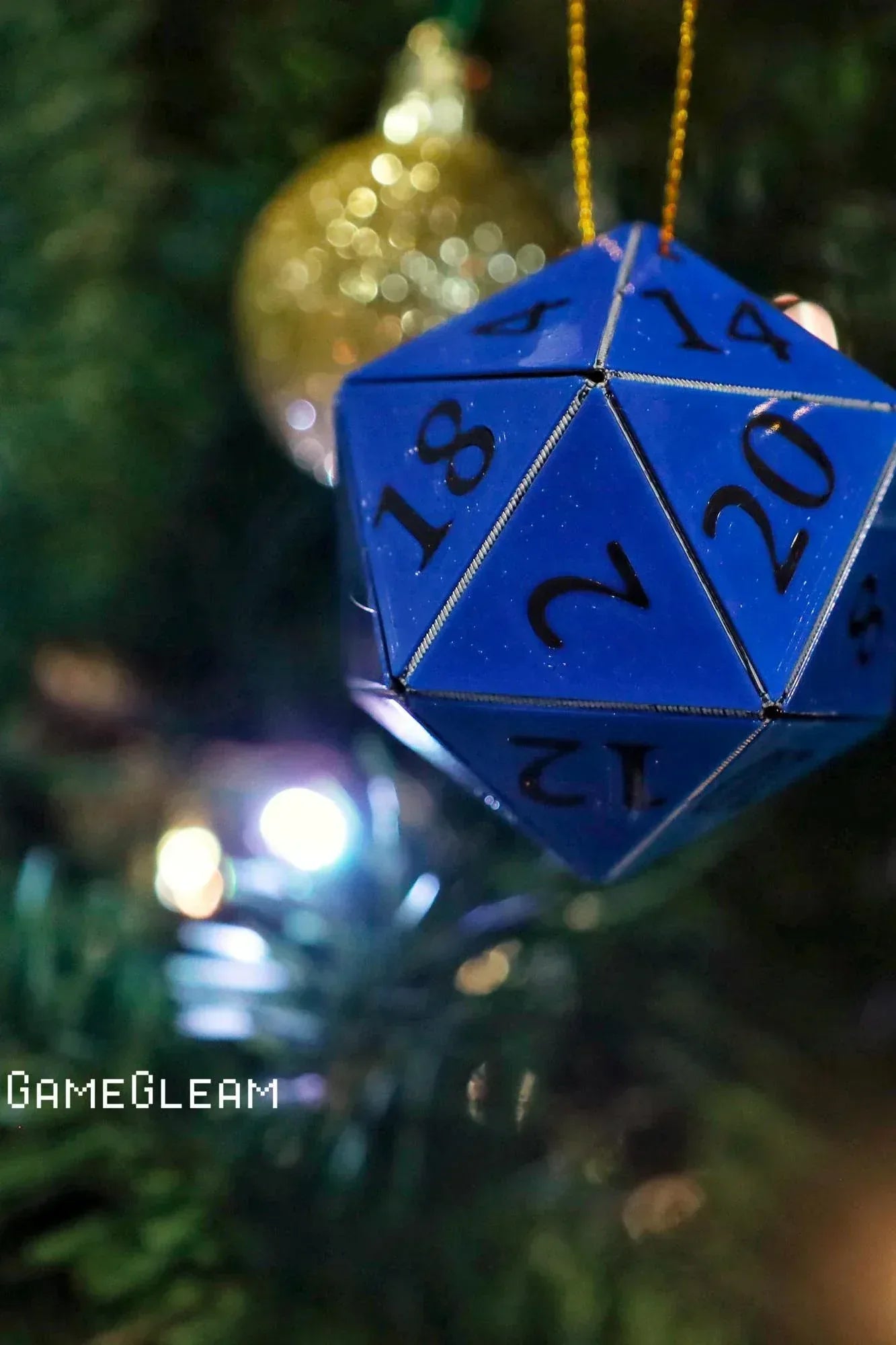 Blue 20-sided dice ornament hanging on a Christmas tree with holiday lights