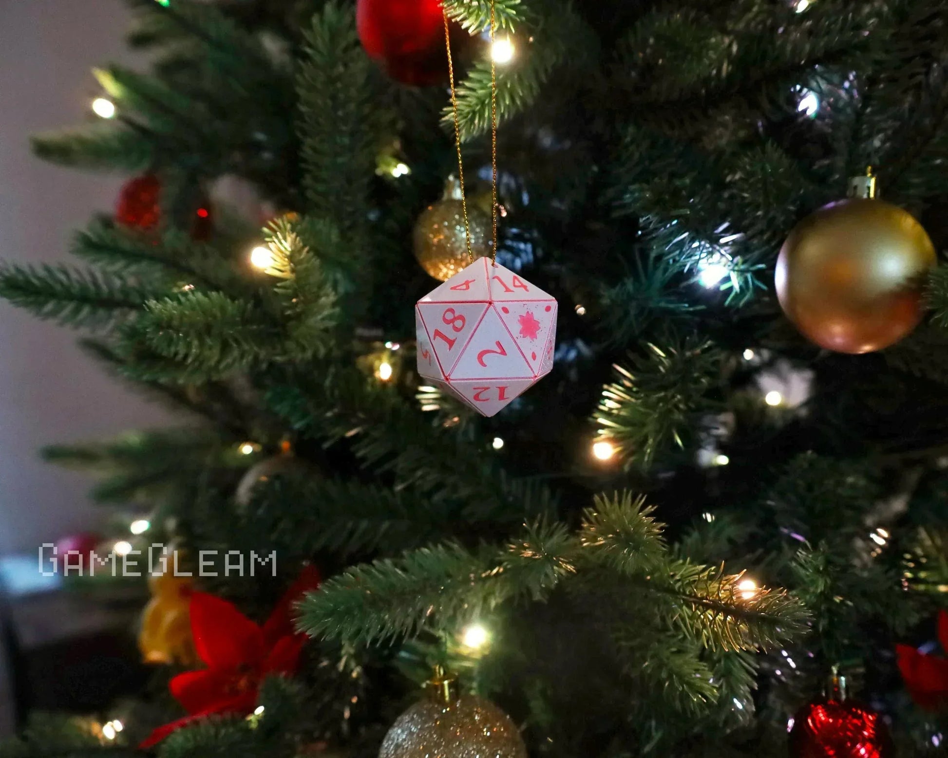White and pink twenty-sided dice ornament hanging on a decorated Christmas tree