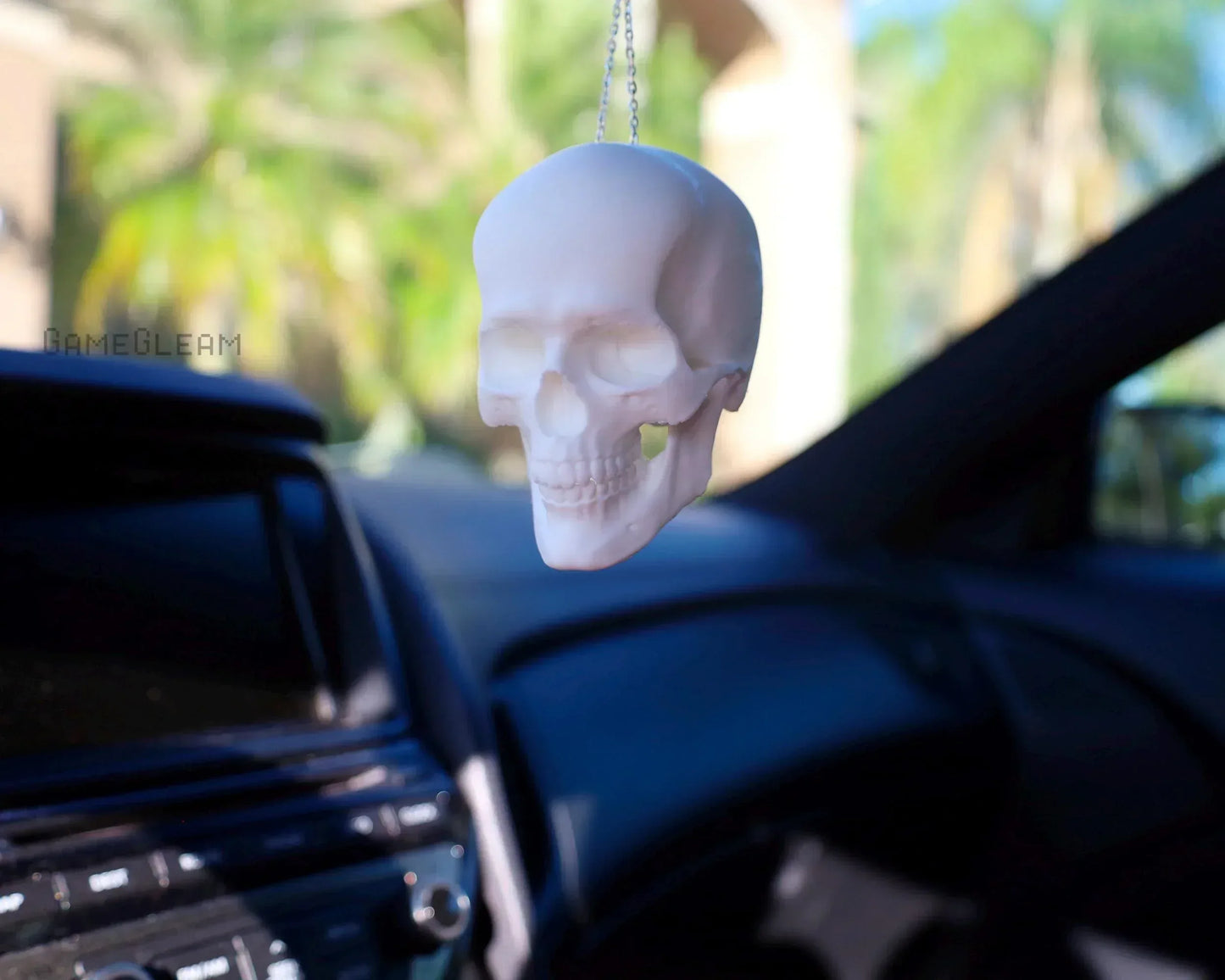 White skull-shaped car charm hanging from rearview mirror in a vehicle interior
