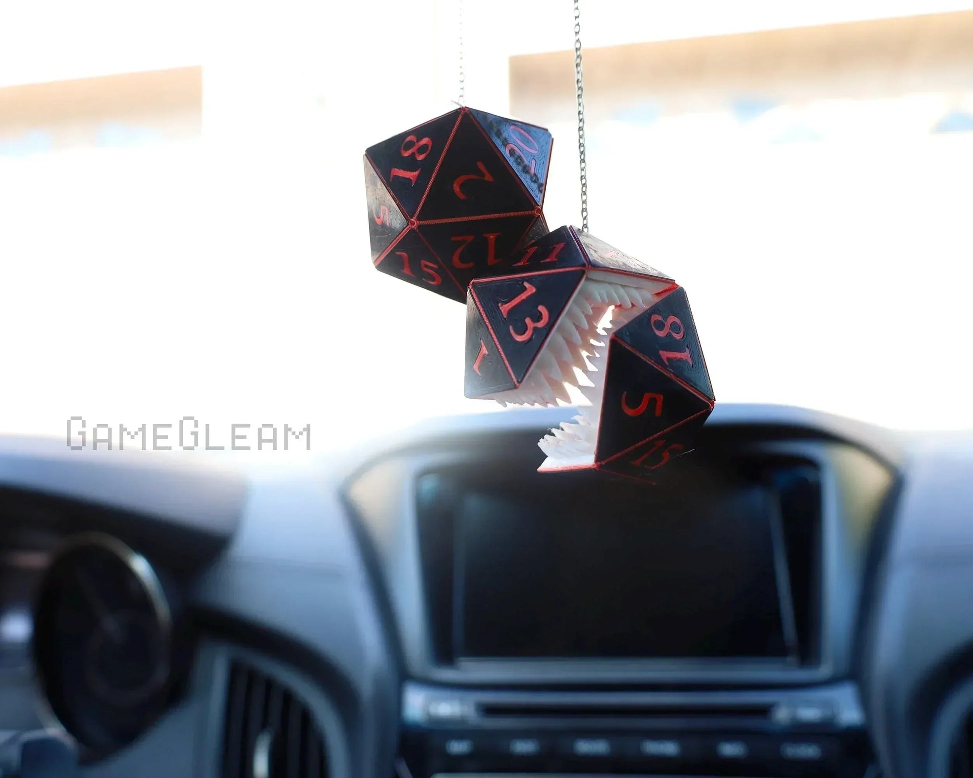 Hanging black and red polyhedral dice charm with teeth in a car, unique gamer accessory