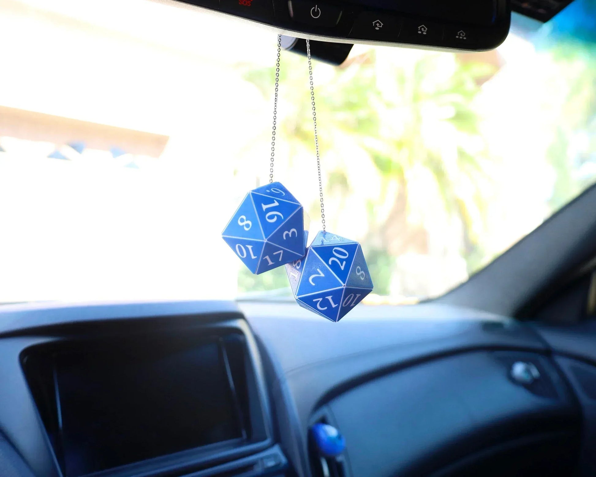 Blue twenty-sided dice car charm hanging from rearview mirror in vehicle interior