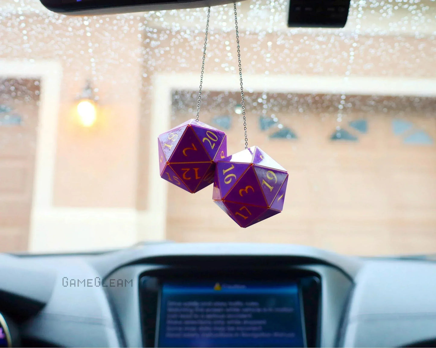 Hanging purple 20-sided dice car charm with gold numbers, photographed in a car interior.