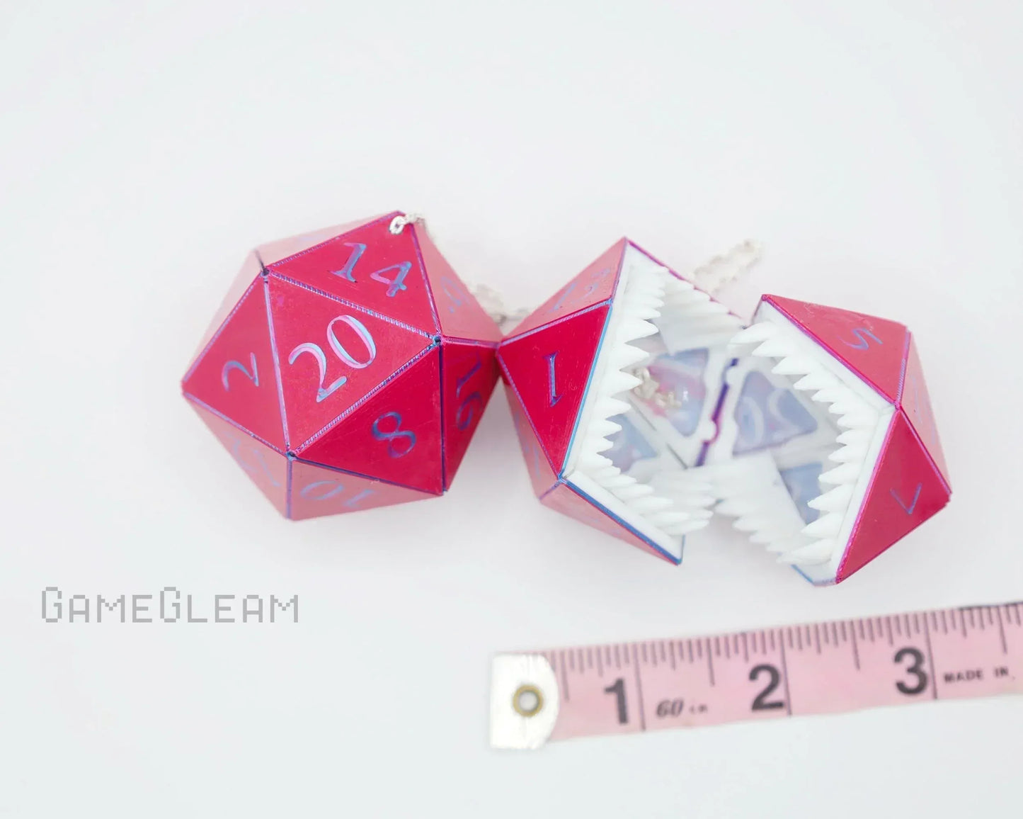 Handmade red and blue 20-sided dice charms with jagged teeth, next to a measuring tape