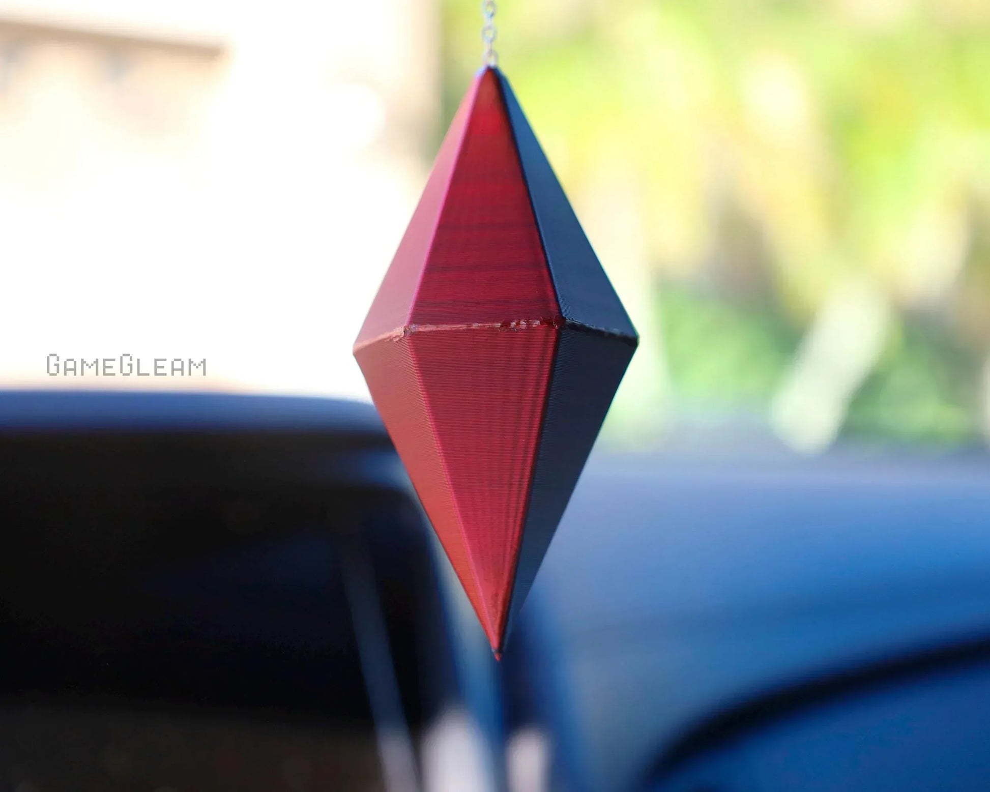 Red and black geometric hanging car dice charm for gamers, displayed inside a vehicle