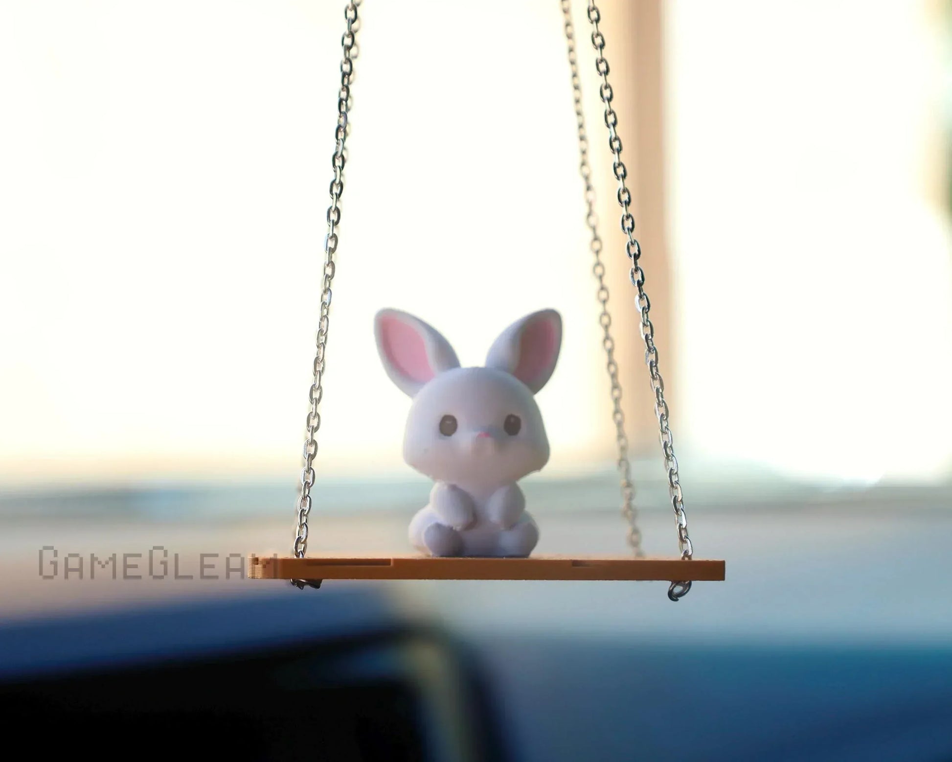 Cute bunny car charm on a swing with chains, hanging from rearview mirror, soft pastel colors