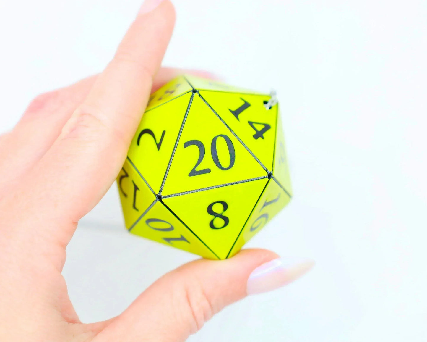 Hand holding a neon yellow 20-sided dice charm for tabletop RPG gaming fans
