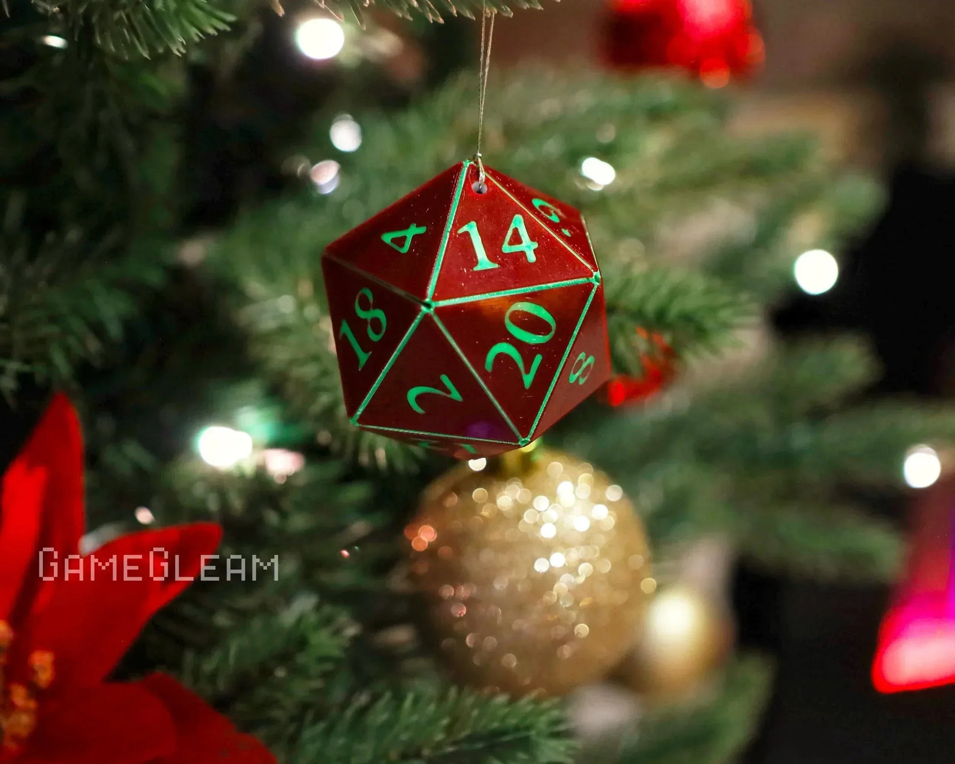 Red twenty-sided dice ornament hanging on a Christmas tree with festive lights.