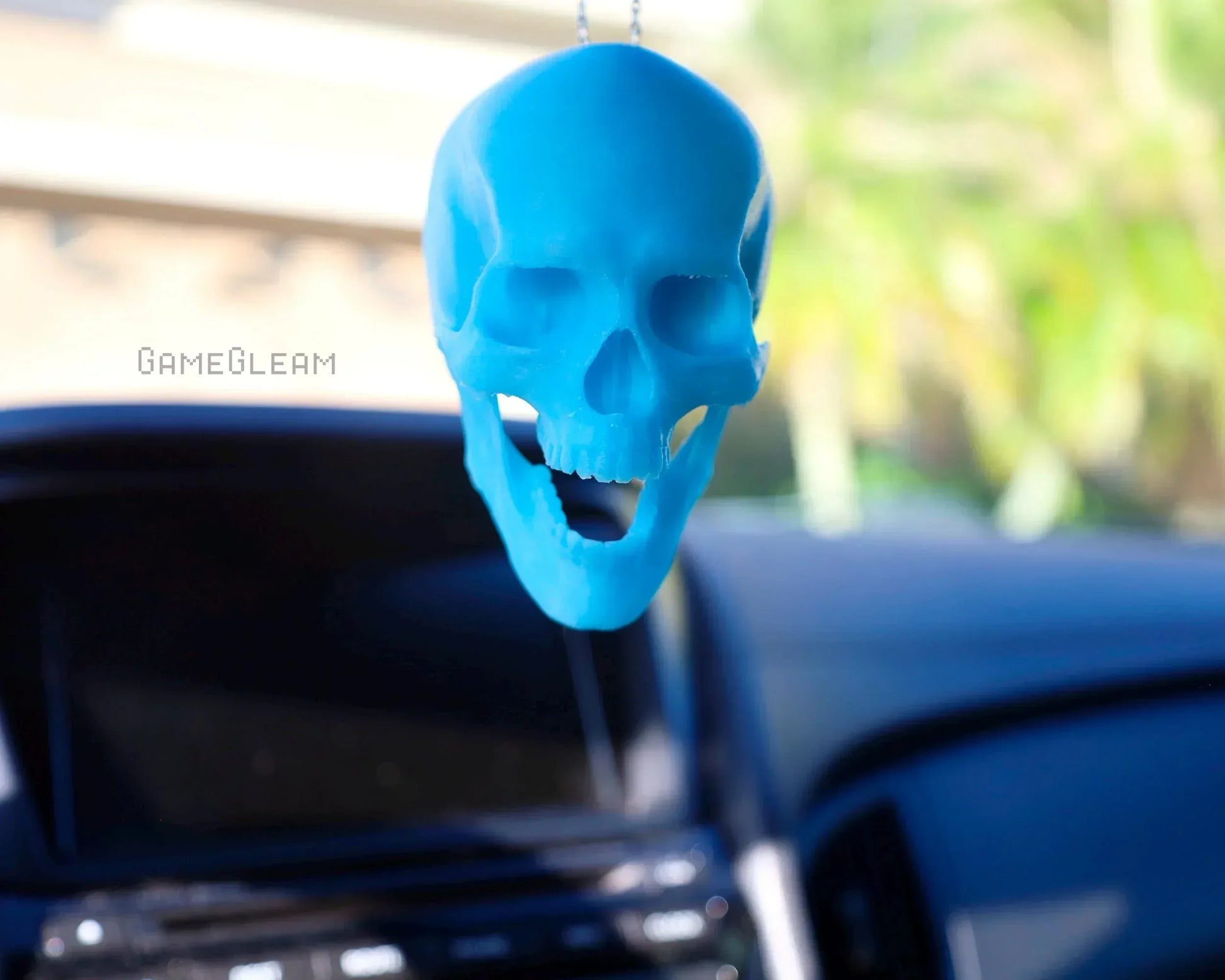 Blue skull-shaped car charm hanging from rearview mirror in vehicle interior