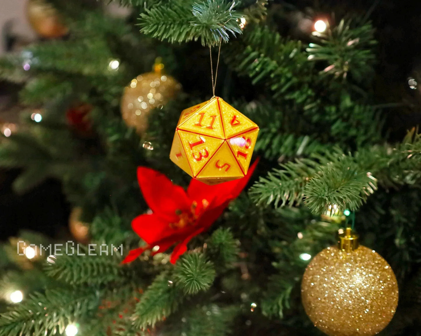 Yellow twenty-sided dice Christmas ornament hanging on a festive tree with red and gold decorations.