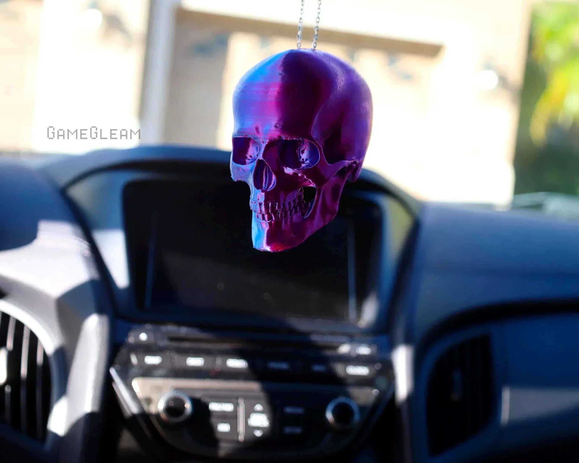 Holographic purple skull car charm hanging on rearview mirror in vehicle interior