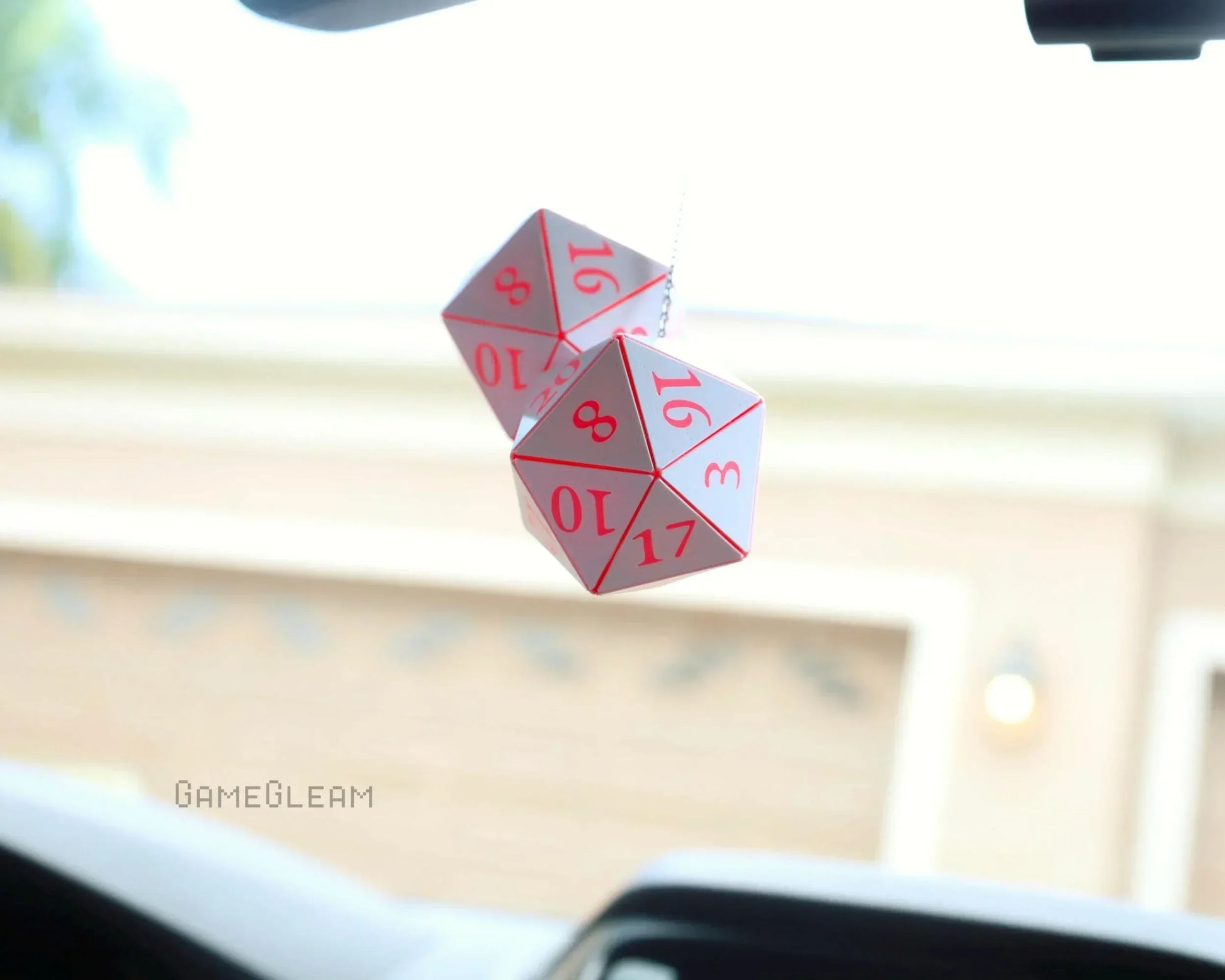 Pink and white twenty-sided dice car charm hanging from rearview mirror