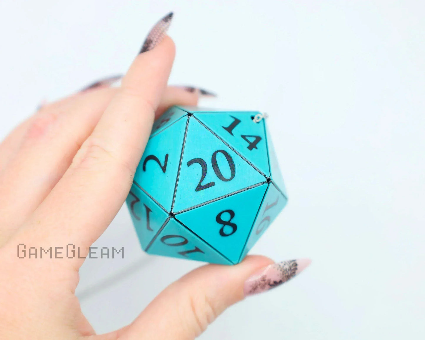 Hand holding a large blue 20-sided dice charm for tabletop gaming fans