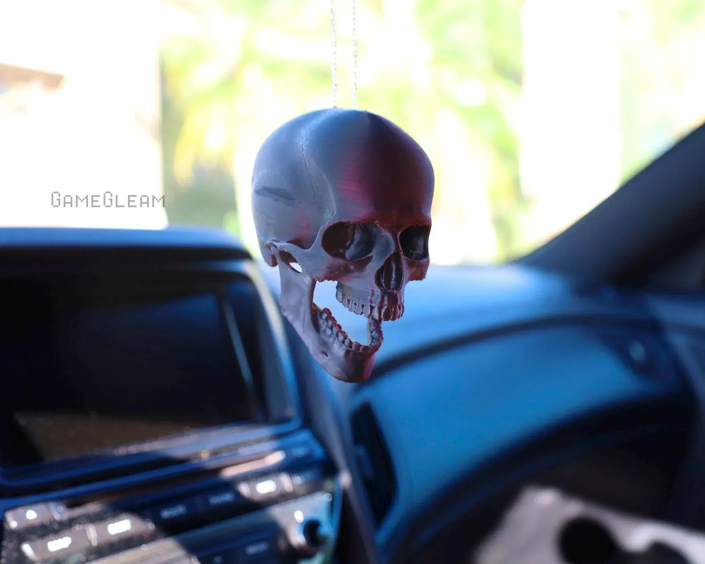 Handmade skull car charm hanging from rearview mirror in a vehicle interior