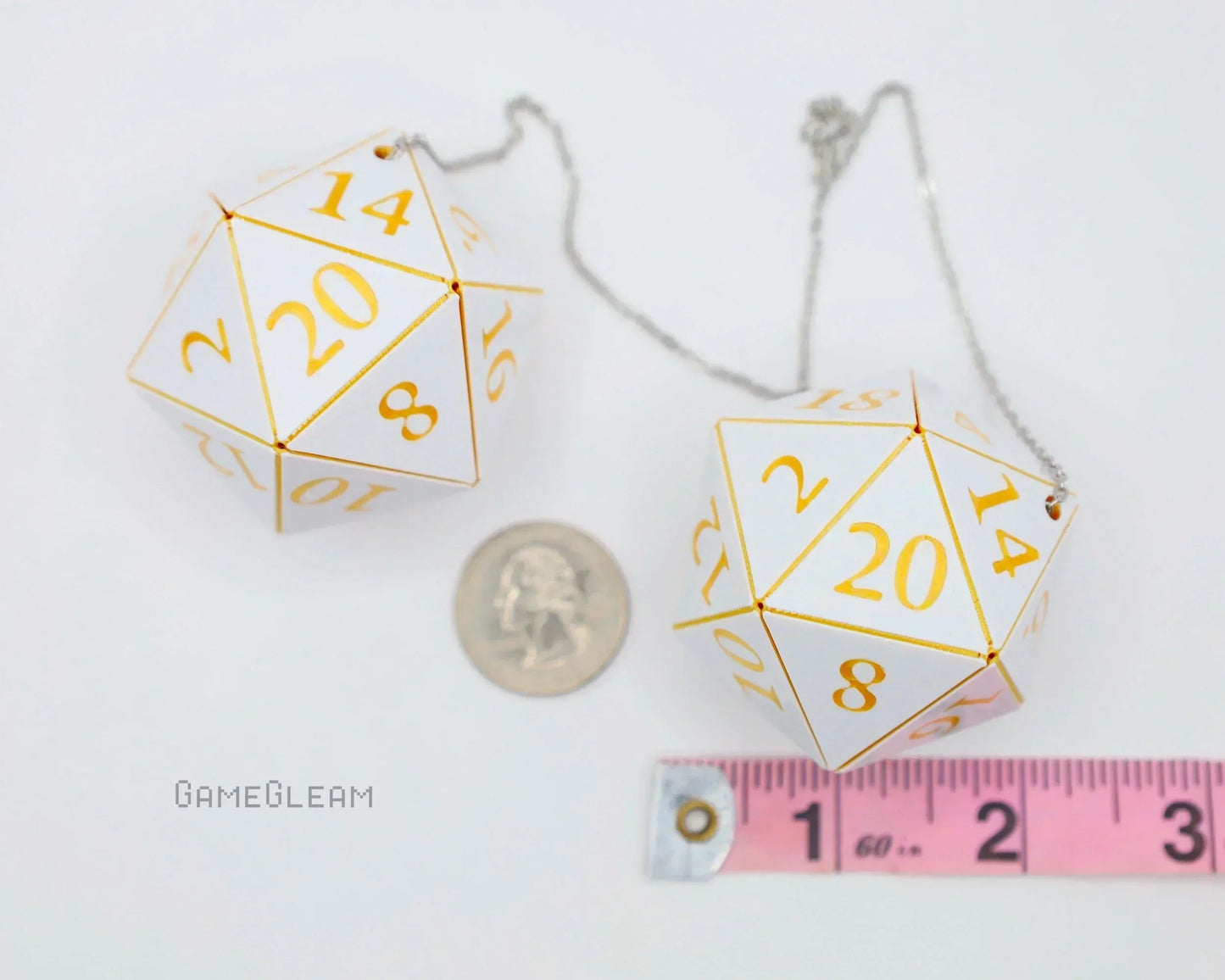 White and gold 20-sided dice car charms with a chain, shown next to a ruler and a coin.