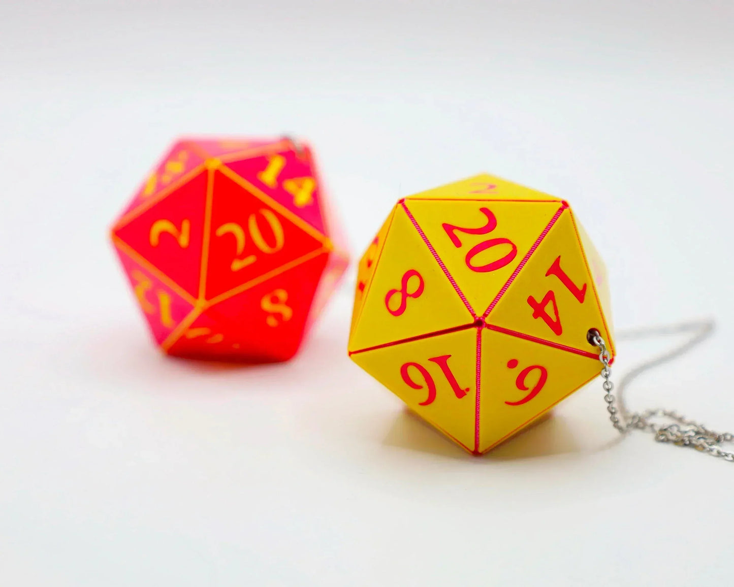 Yellow and red 20-sided dice car accessory with chain on white background