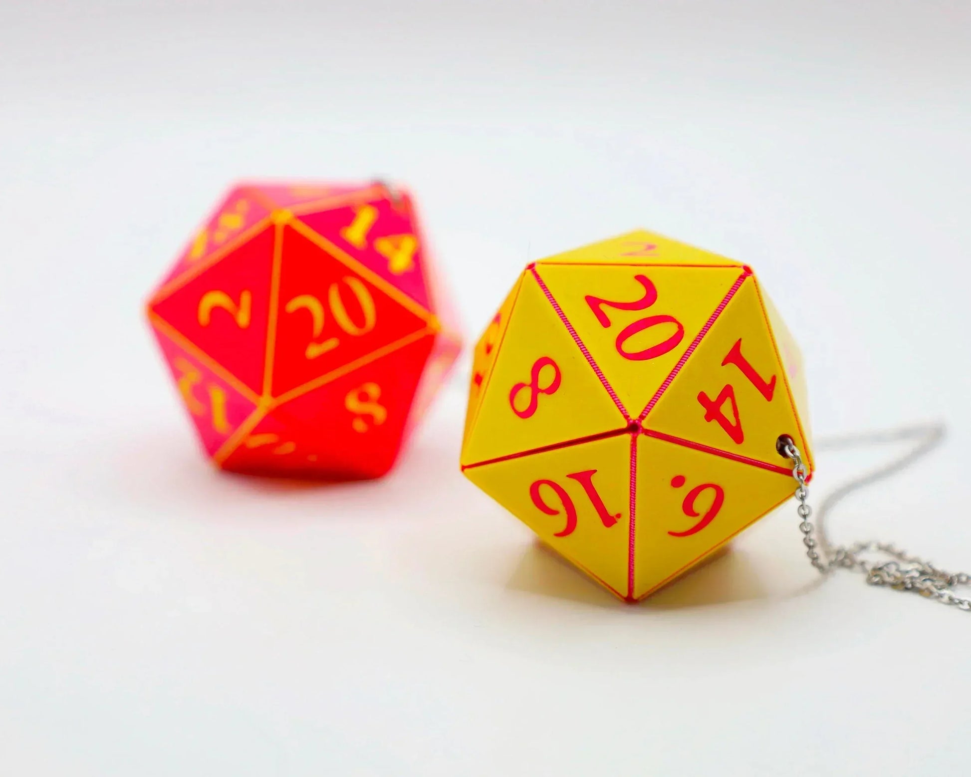 Yellow and red 20-sided dice car accessory with chain on white background