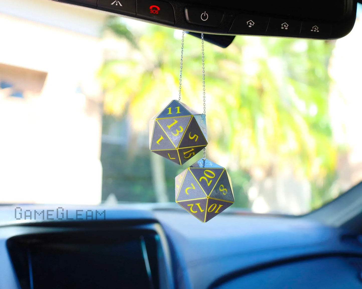 Hanging set of two holographic twenty-sided dice car charm with yellow numbers in vehicle interior