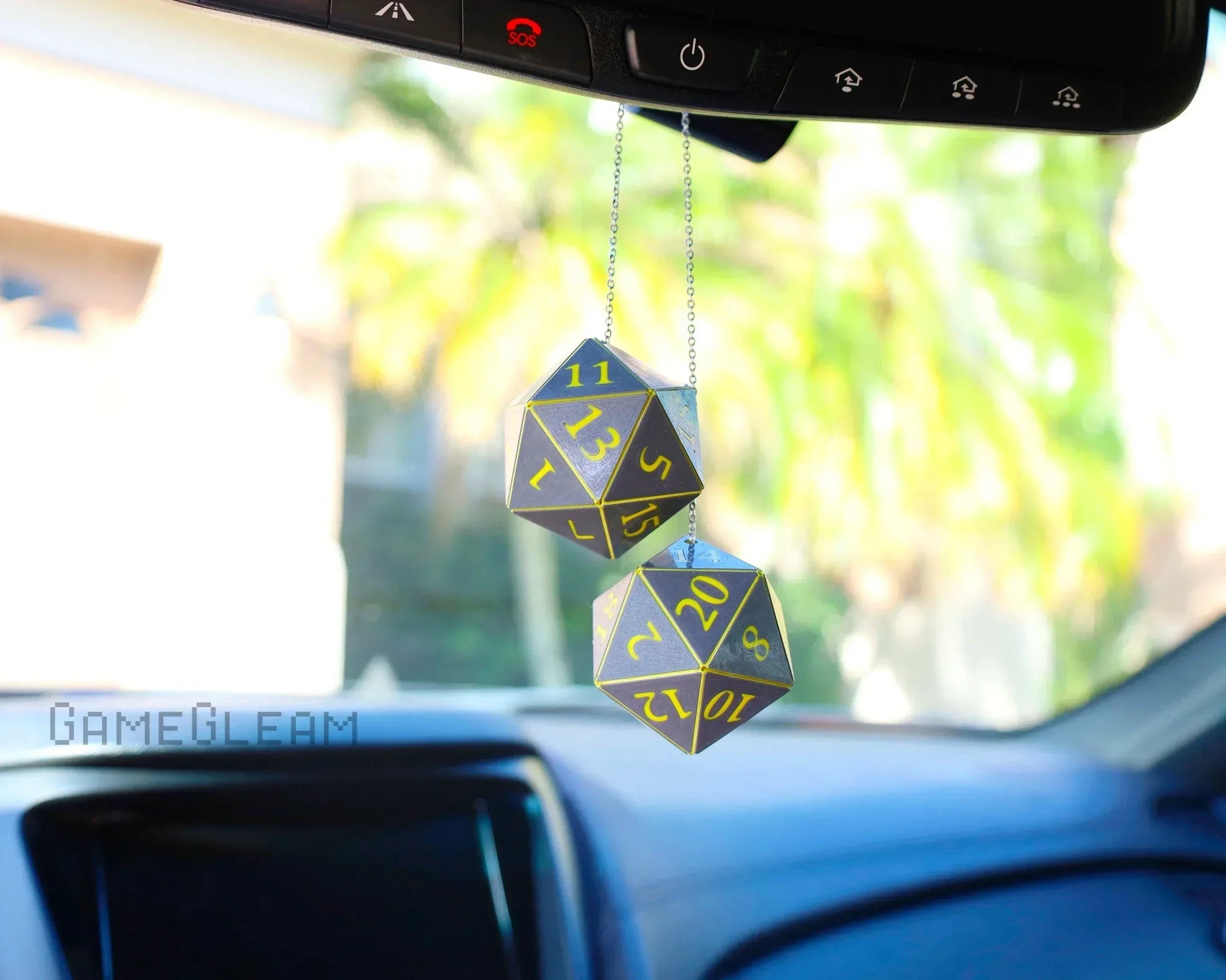 Hanging set of two holographic twenty-sided dice car charm with yellow numbers in vehicle interior