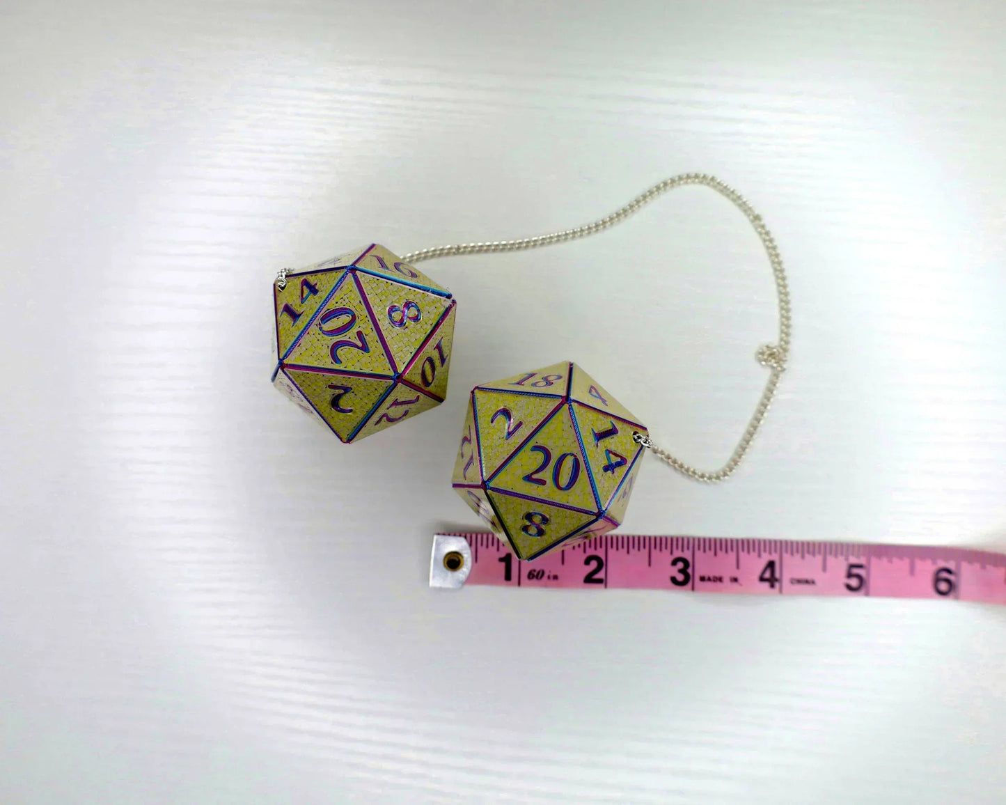 Holographic twenty-sided dice car pendant with chain and a measuring tape on white background