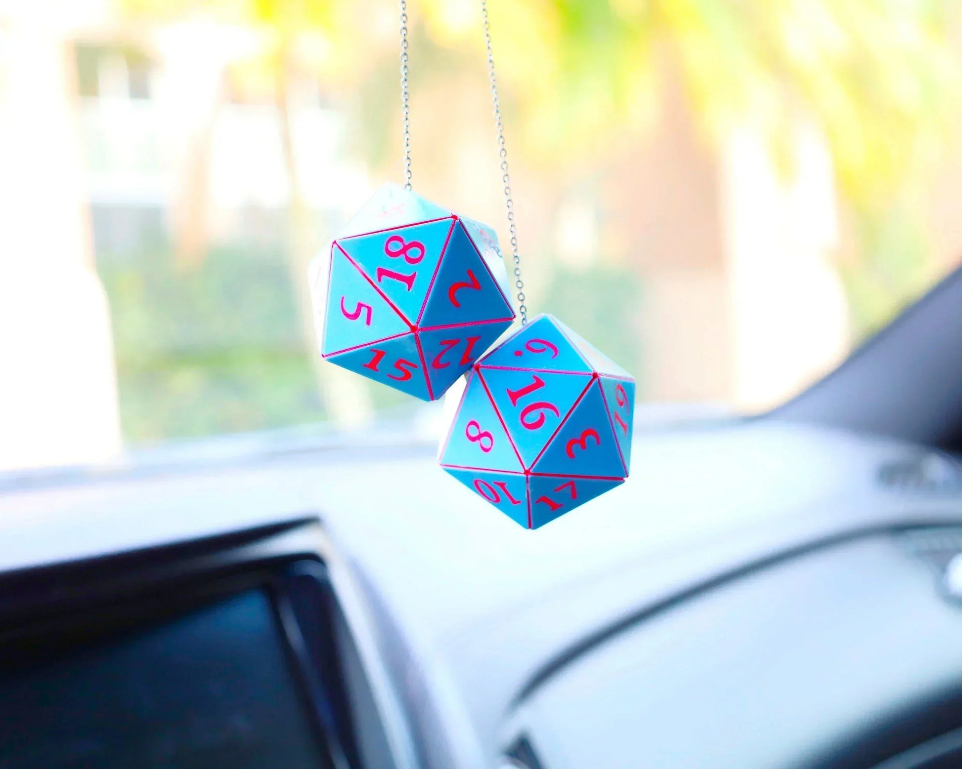 Pair of blue and pink 20-sided dice car charms hanging from rearview mirror