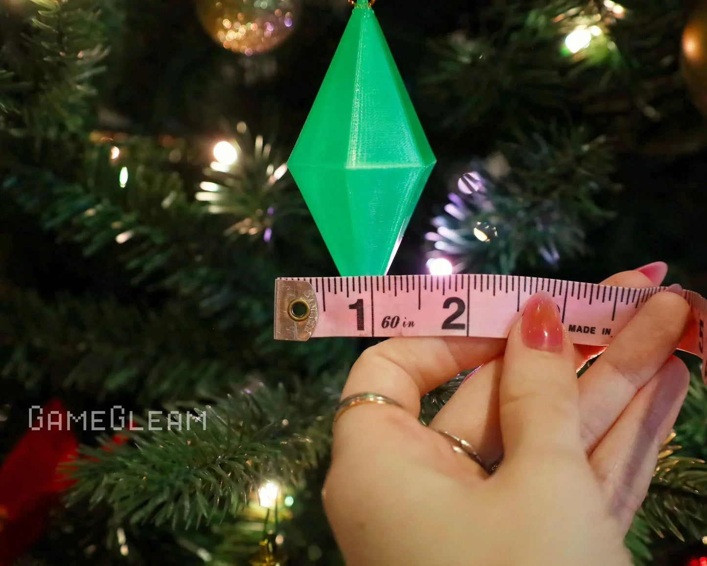 Green polyhedral dice charm ornament measured by tape on Christmas tree