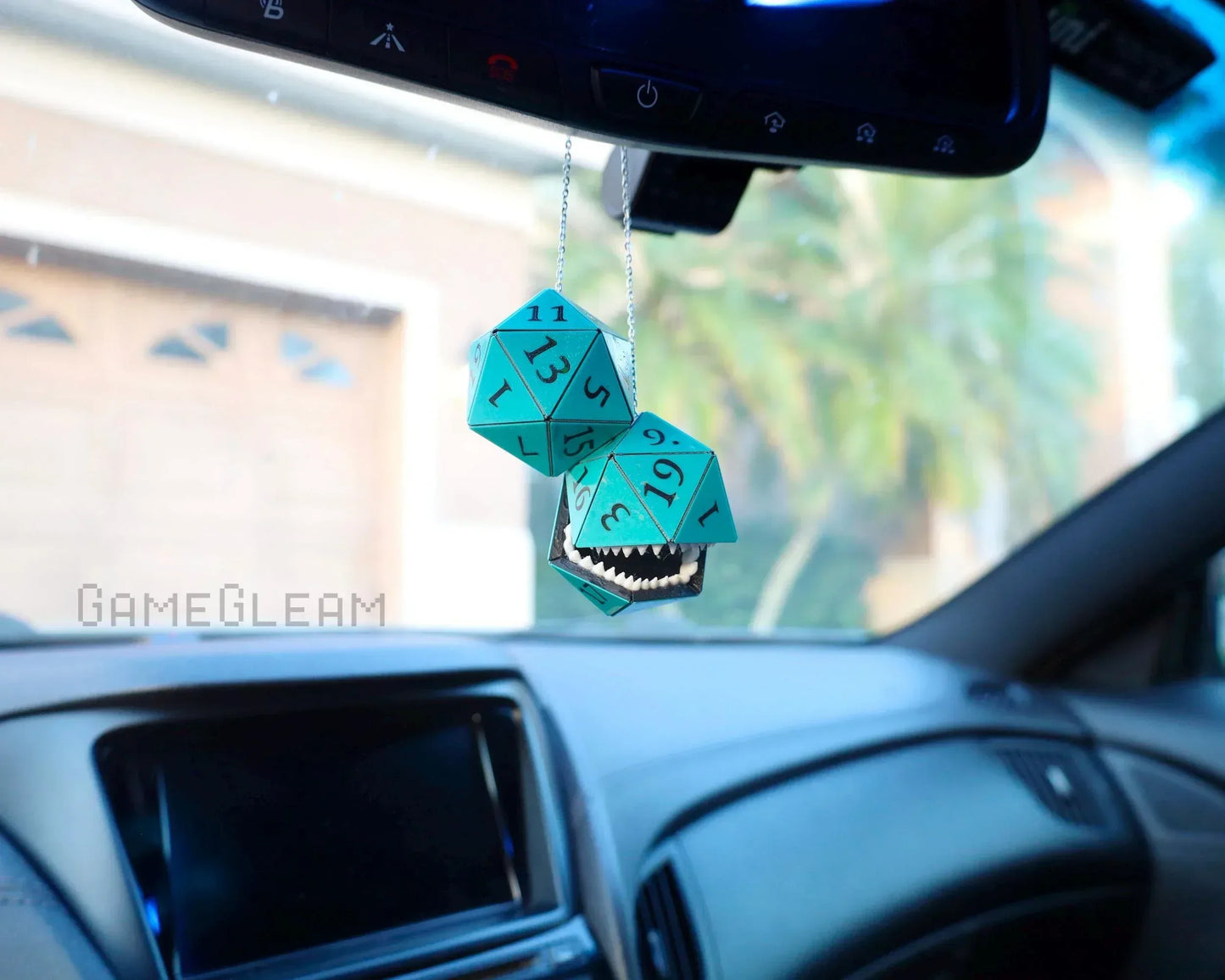 Turquoise twenty-sided dice car charm with smiling mouth accent hanging from rearview mirror