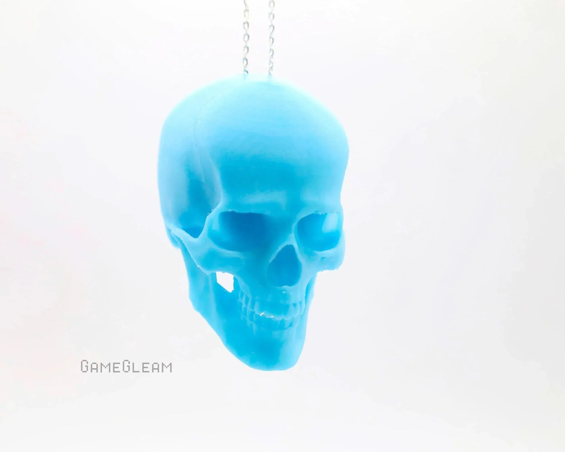 Blue skull-shaped car charm on chain with minimalist white background
