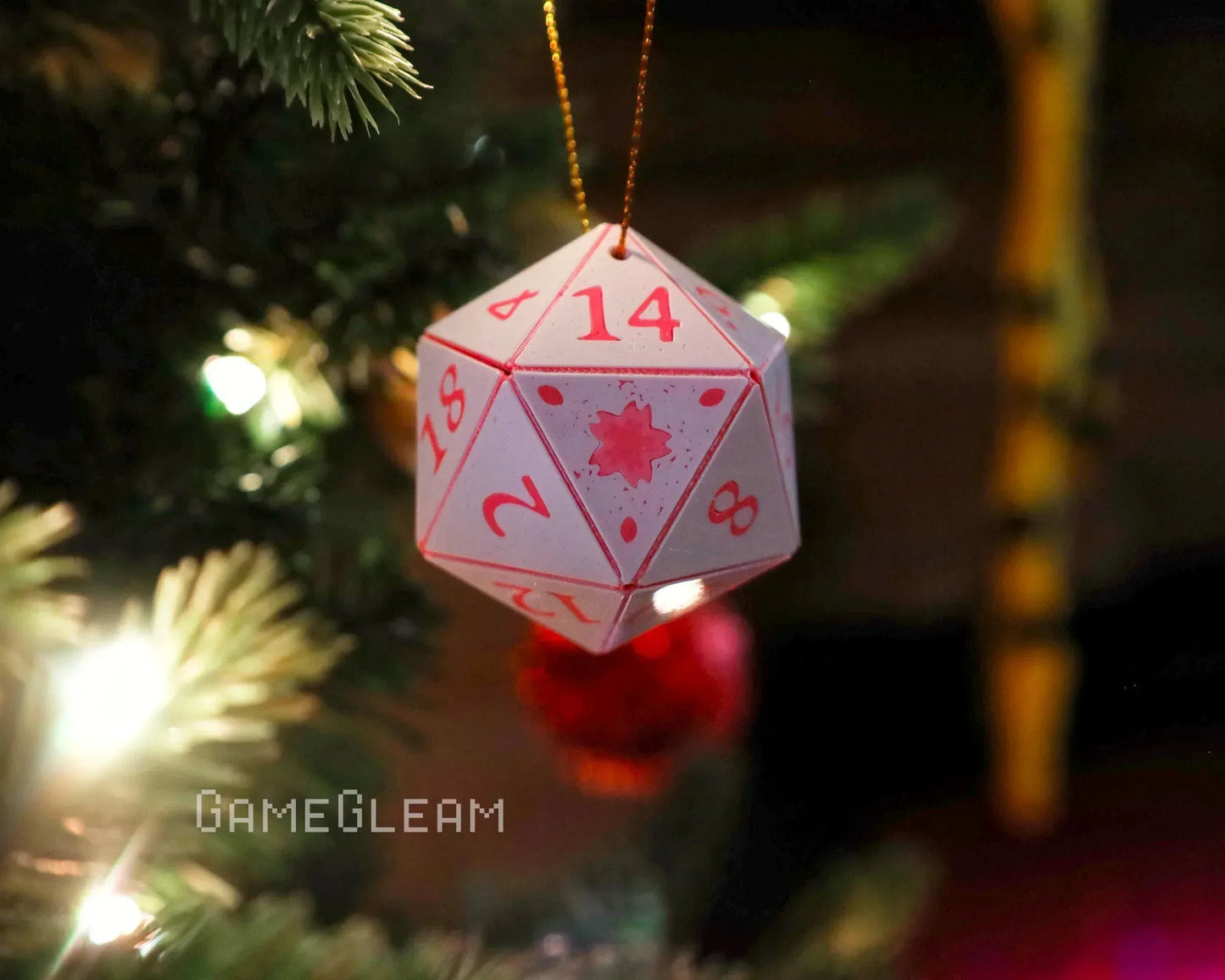 Handmade 20-sided dice ornament with red numbers hanging on a lit Christmas tree.