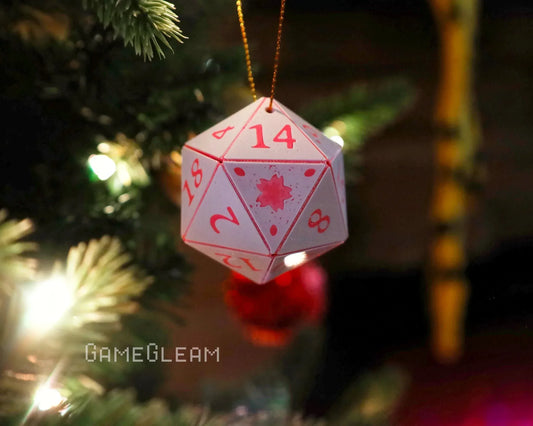 Handmade 20-sided dice ornament with red numbers hanging on a lit Christmas tree.