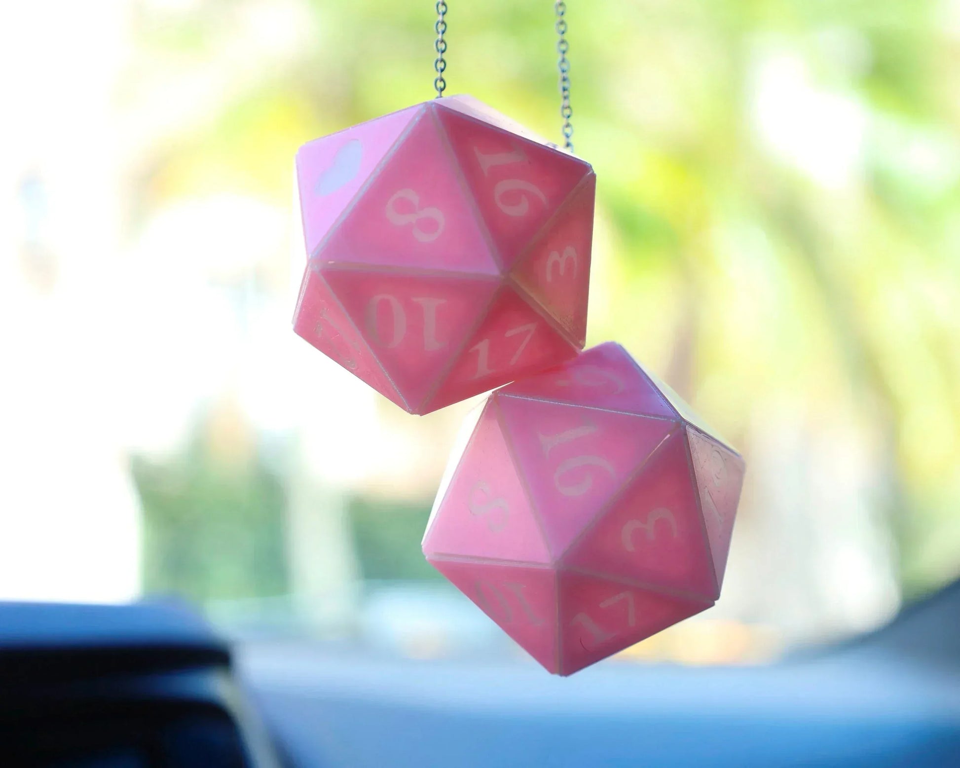 Pink twenty-sided dice car charm hanging from a rearview mirror, gamer accessory