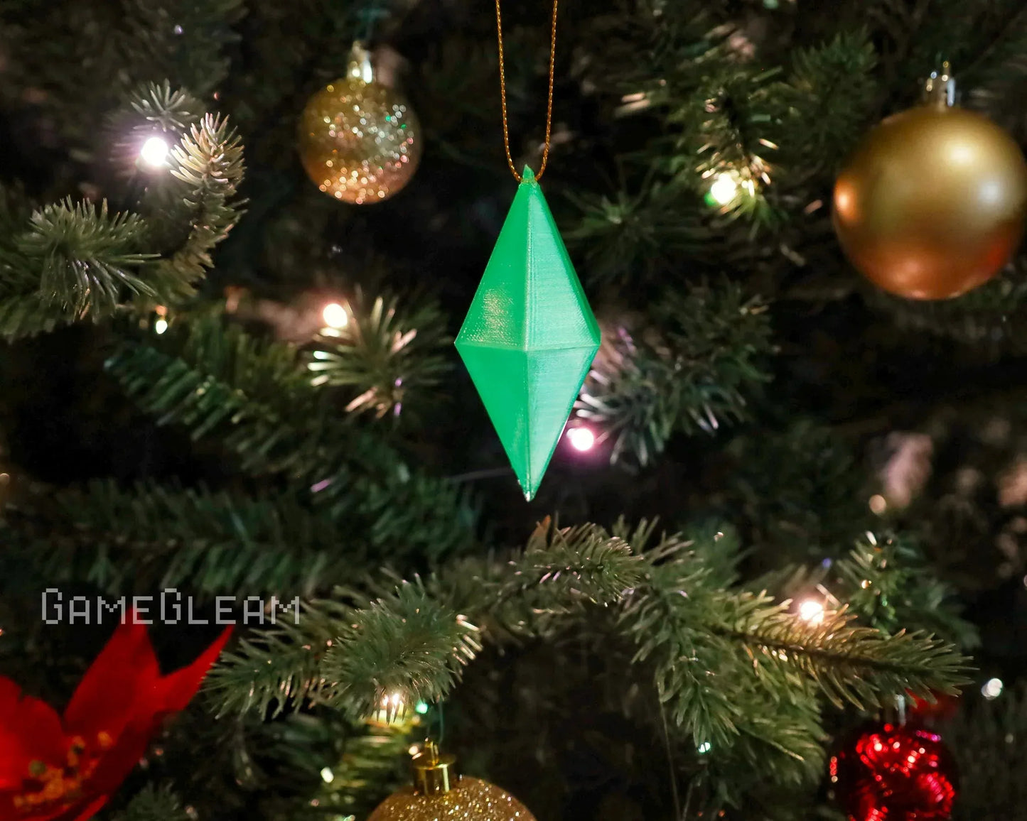 Green geometric ornament hanging on Christmas tree with gold and red baubles