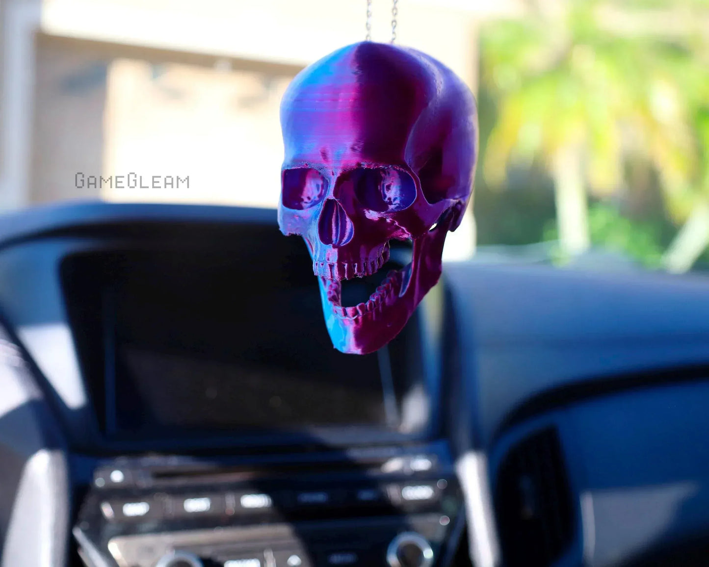 Holographic purple skull car charm hanging from rearview mirror in modern car interior