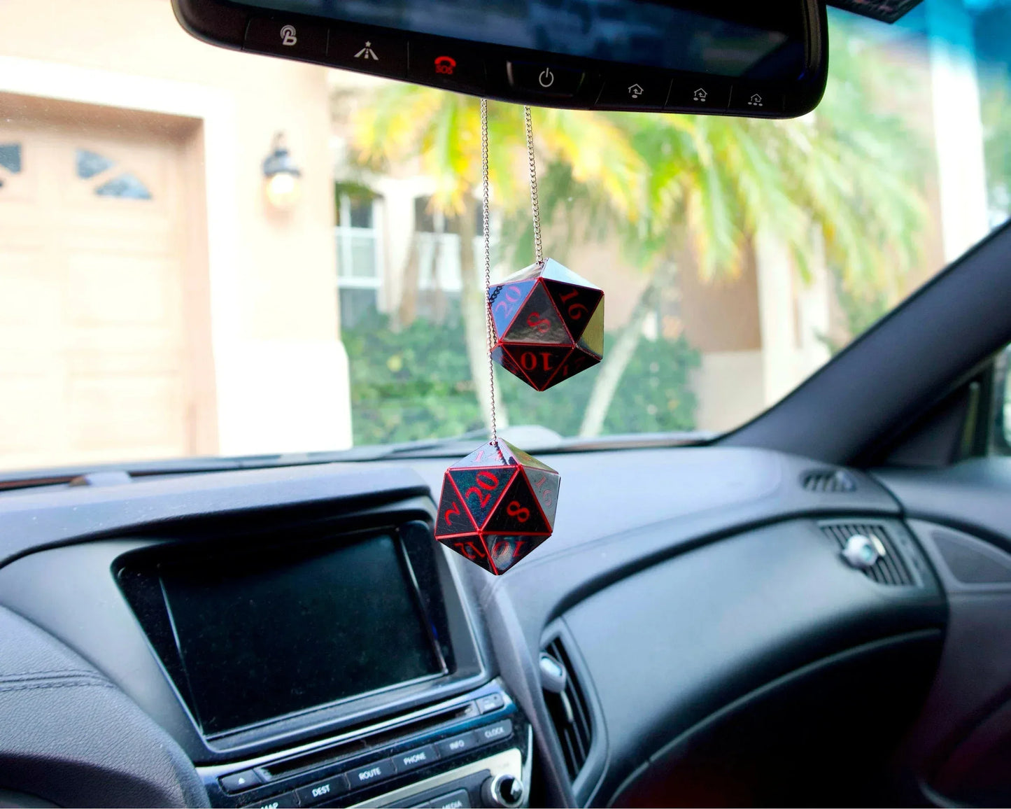 Two black and red twenty-sided dice hanging from a car mirror as gamer-themed car accessories.